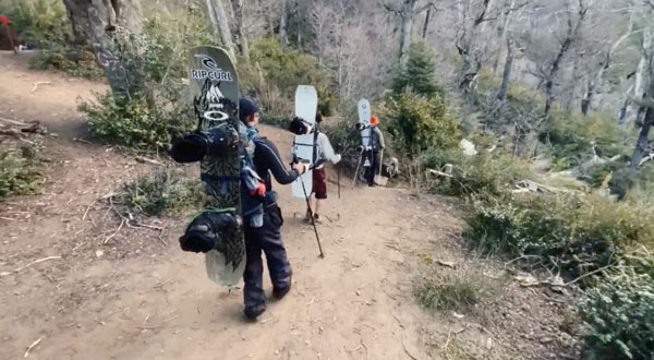 Jones snowboarders hiking the forest in Cerro Lopez, Argentina