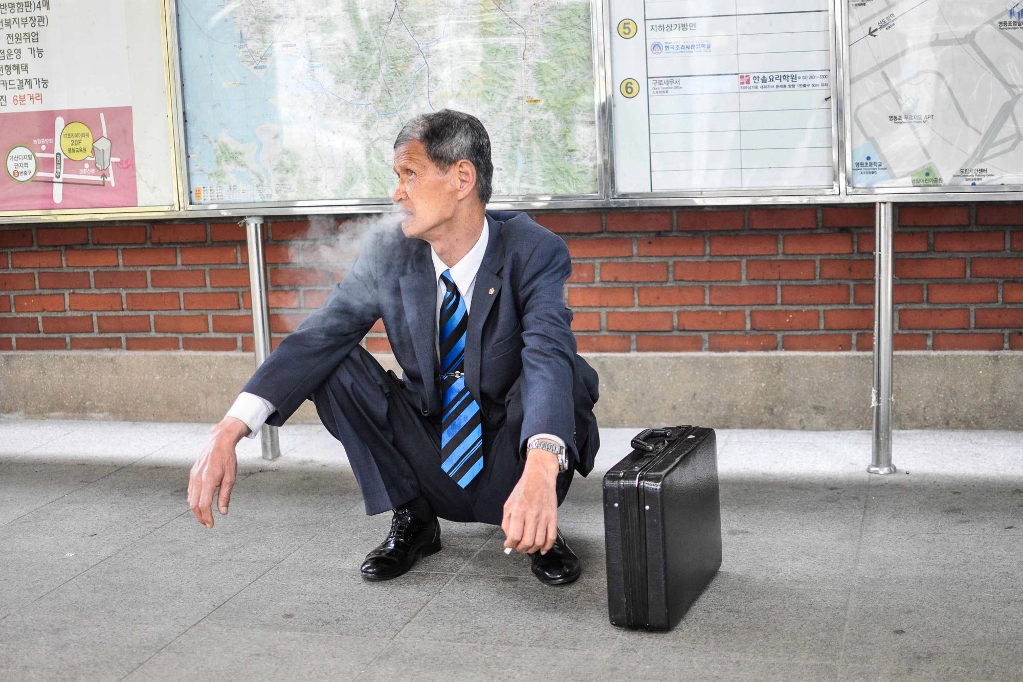 Man comfortably waiting for a train in the deep squat position